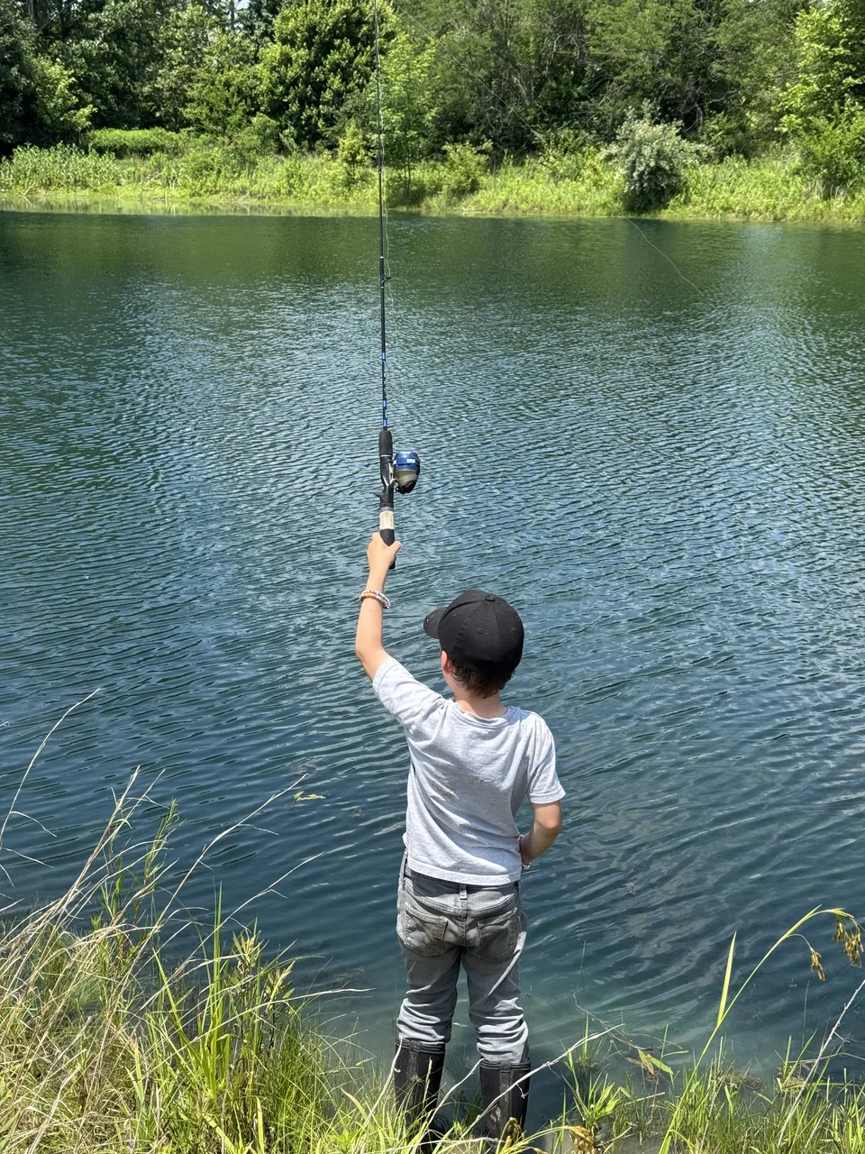 Young camper casting a fishing rod into the farm pond