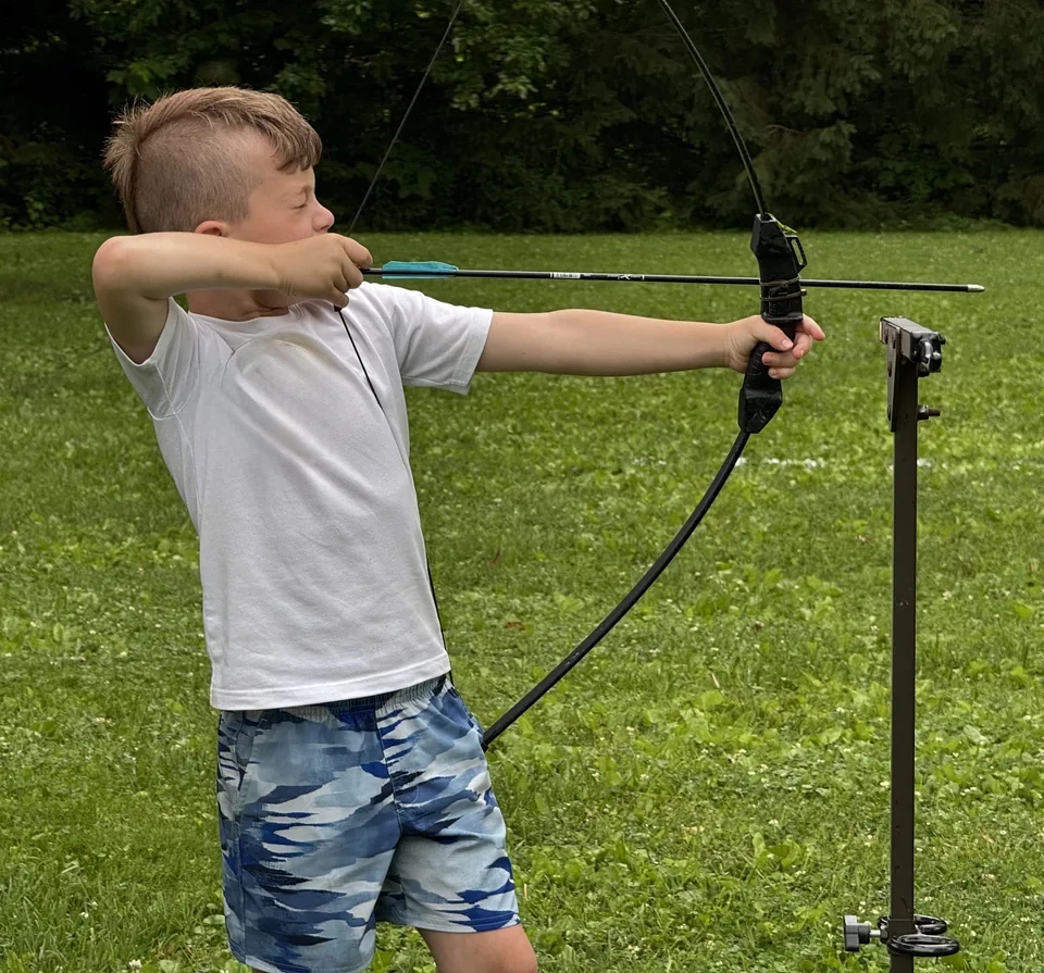 Camper drawing back a bow at archery