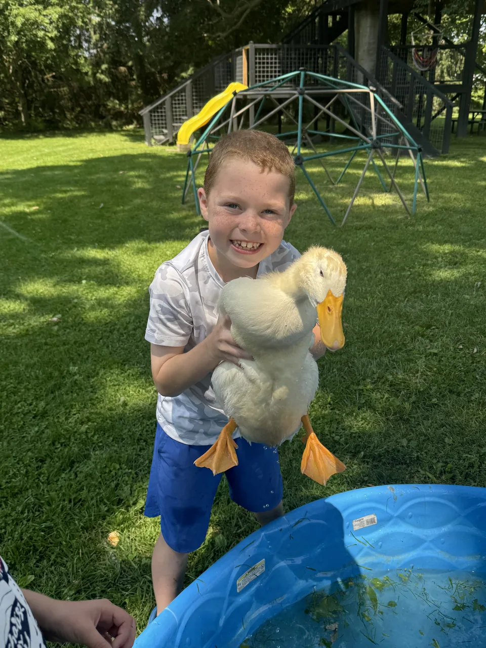 Camper holding a white duck by the kiddie pool